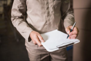 Close up mid section of warehouse worker with clipboard in warehouse