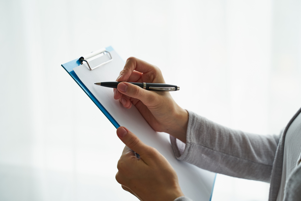 woman holding clipboard and writing on it, concept of work with documents and information