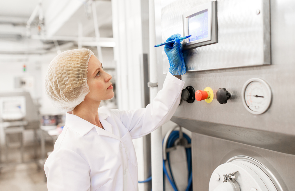 manufacture, industry, production and people concept - woman programming industrial equipment with computer at ice cream factory